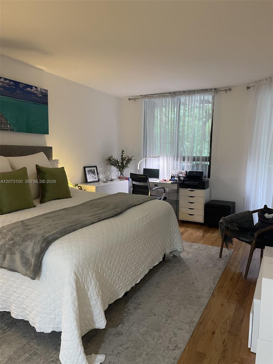 Bedroom featuring wood-finish flooring and multiple windows with curtain hardware