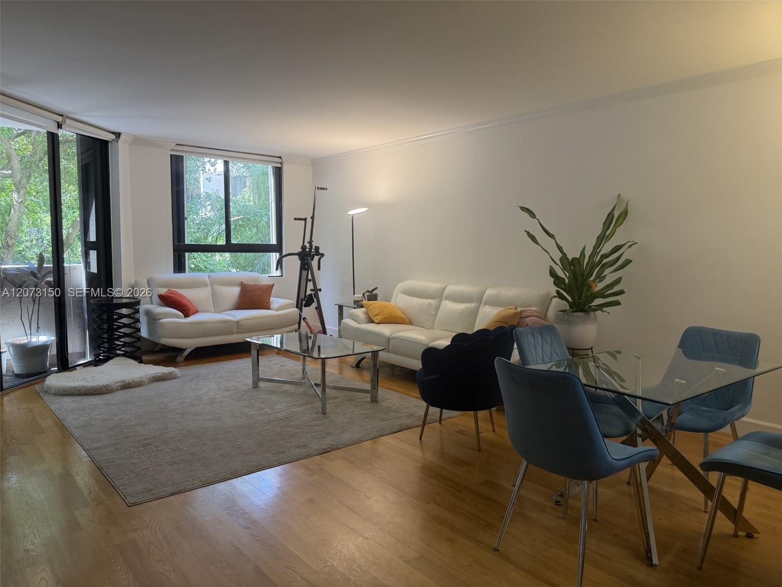 Open-concept living space featuring wood-finish flooring, floor-to-ceiling sliding glass doors, and expansive windows