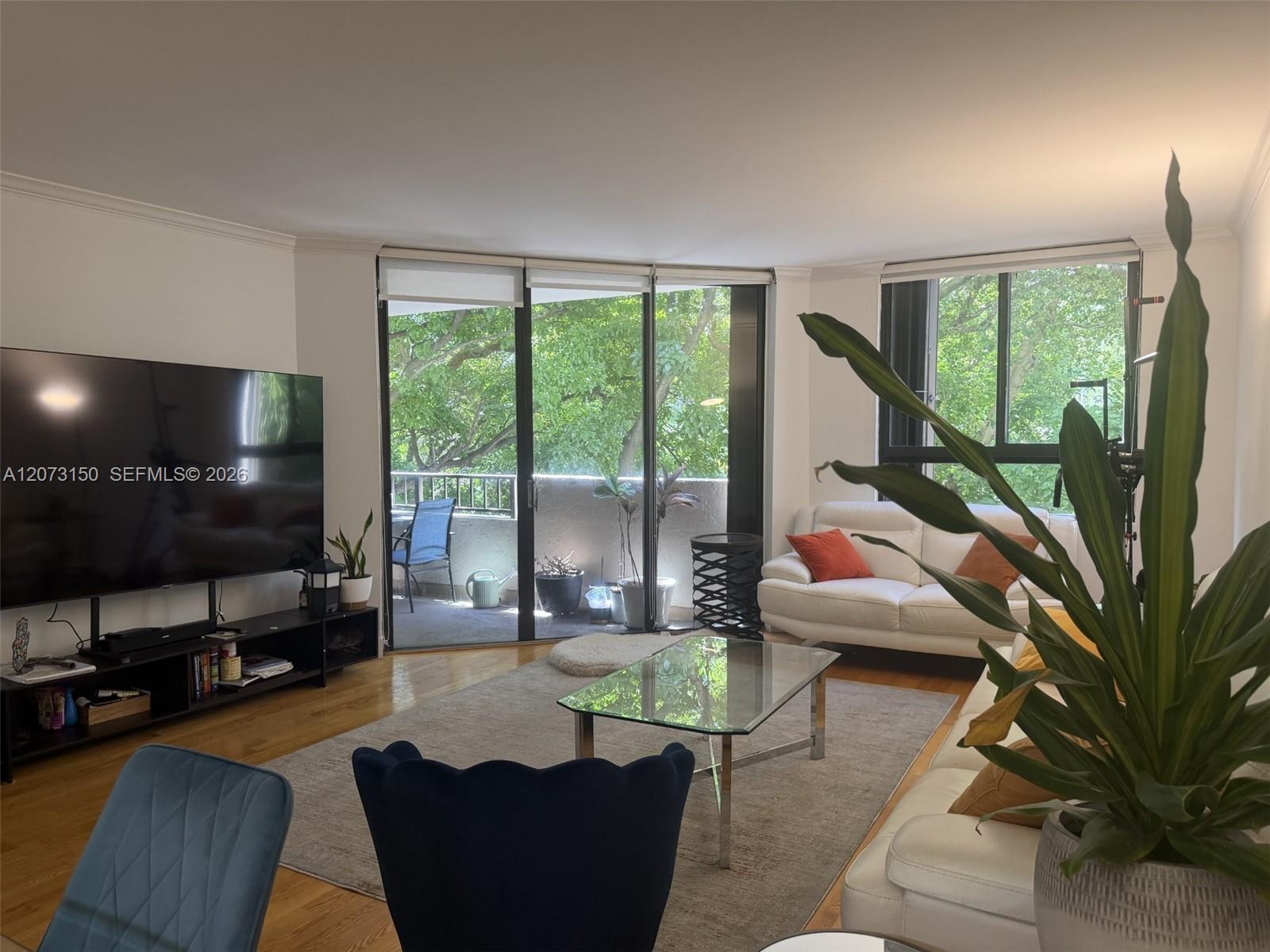 Living area featuring wood-finish flooring, floor-to-ceiling sliding glass doors, and a private balcony