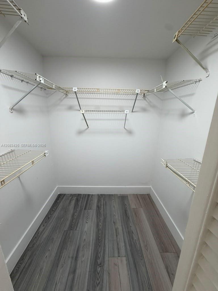 Walk-in storage space featuring wood-finish flooring and multi-level white wire shelving