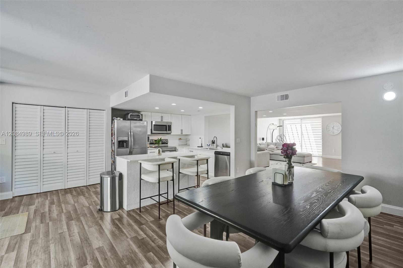 Kitchen featuring a central island with a solid surface countertop, white cabinetry, stainless steel appliances, and recessed lighting, finished with wood-finish flooring