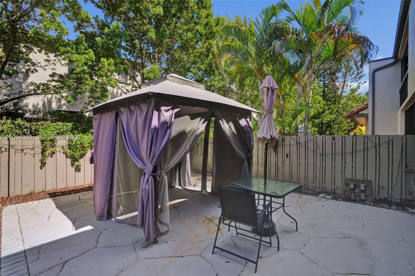 Flagstone-style patio featuring a privacy fence and mature landscaping