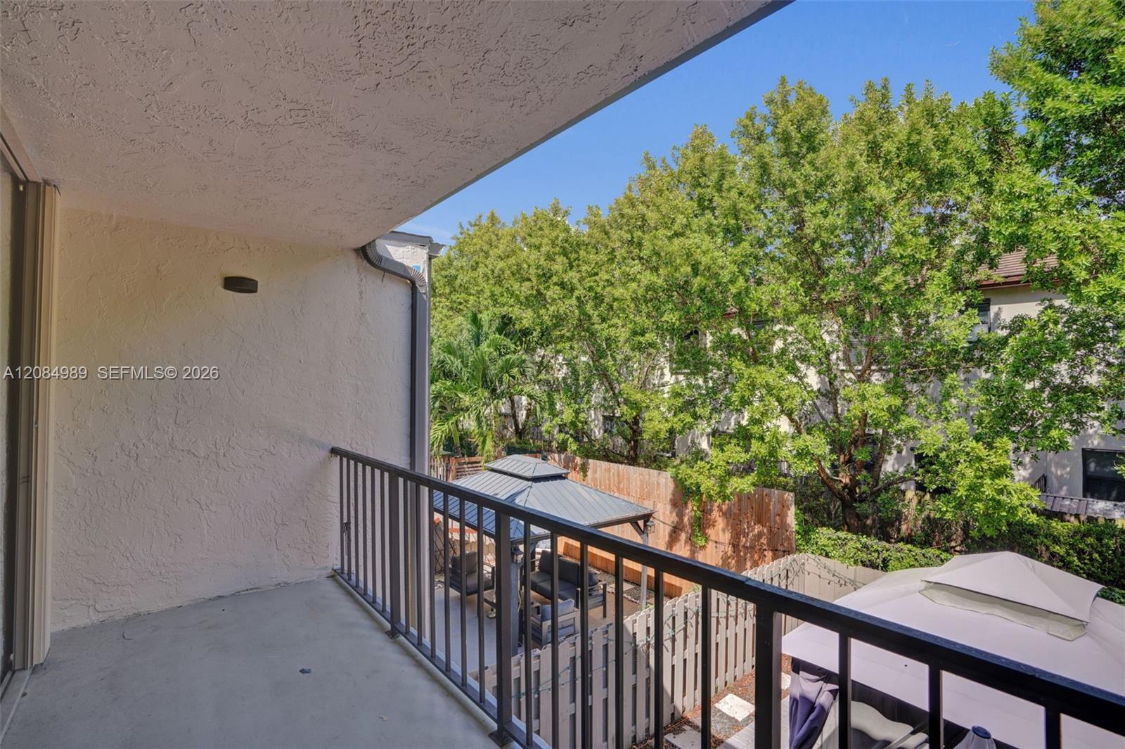 Covered balcony featuring a concrete floor, stucco wall finish, and metal railing