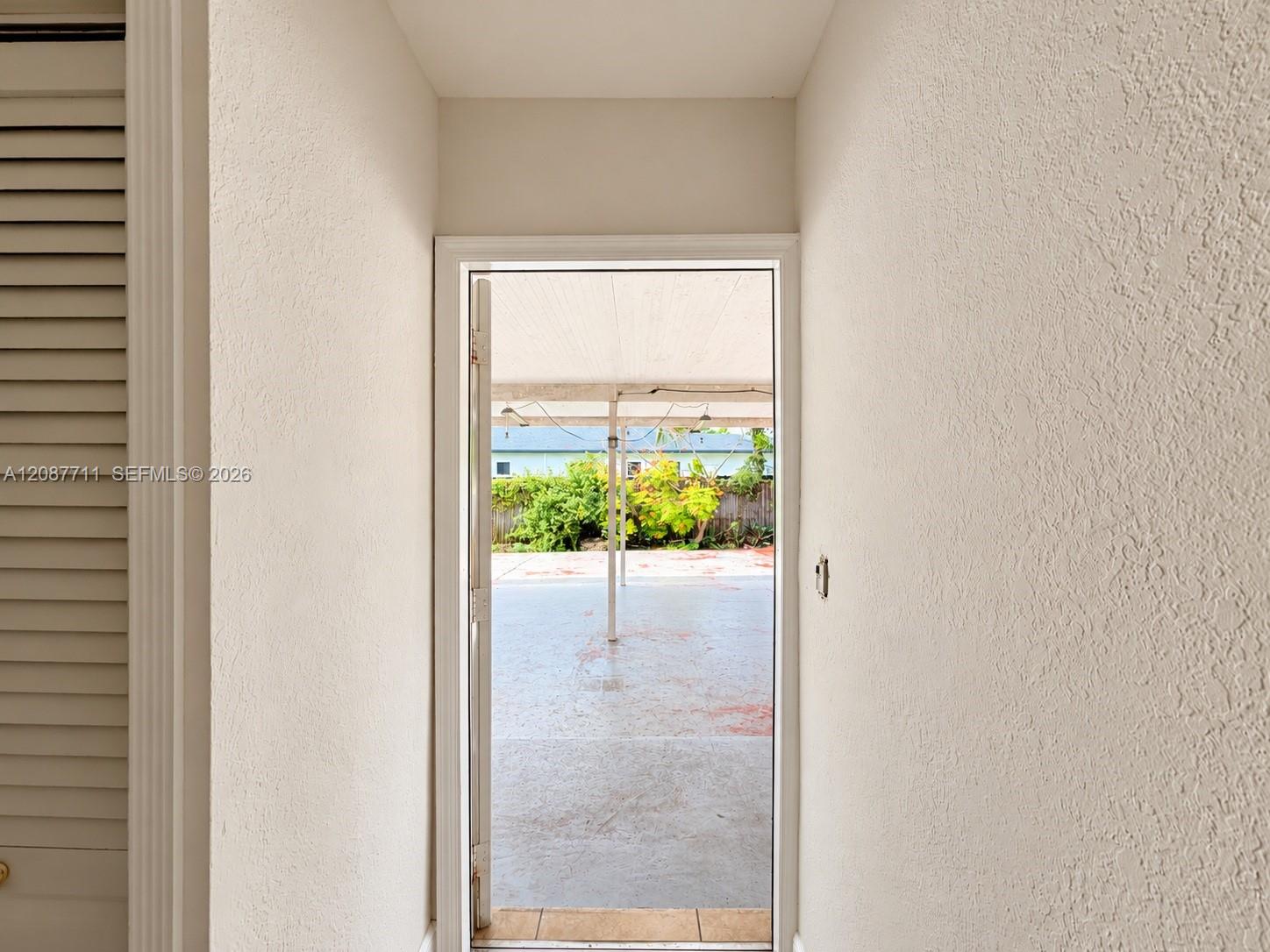 Entryway featuring louvered bi-fold closet doors and a glass-paneled exterior door opening to a concrete patio with a covered structure