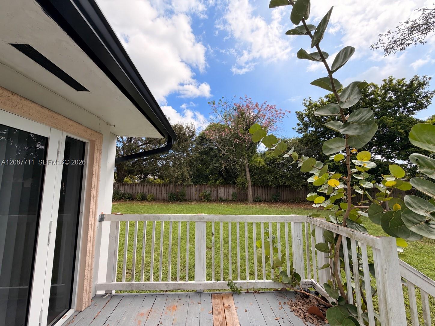 Outdoor deck featuring white wooden railings, grey plank flooring, and dual glass-paneled exterior doors