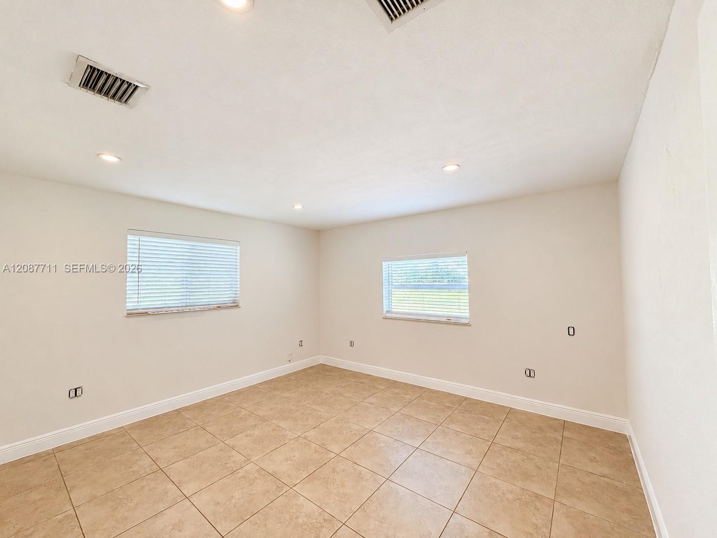 Neutral-toned tile flooring, recessed ceiling lighting, and dual windows with horizontal blinds