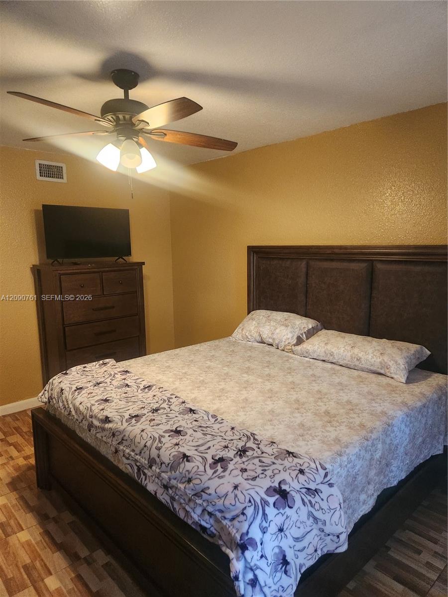 Textured walls, multi-tone tiled flooring, and a multi-blade ceiling fan with integrated lighting