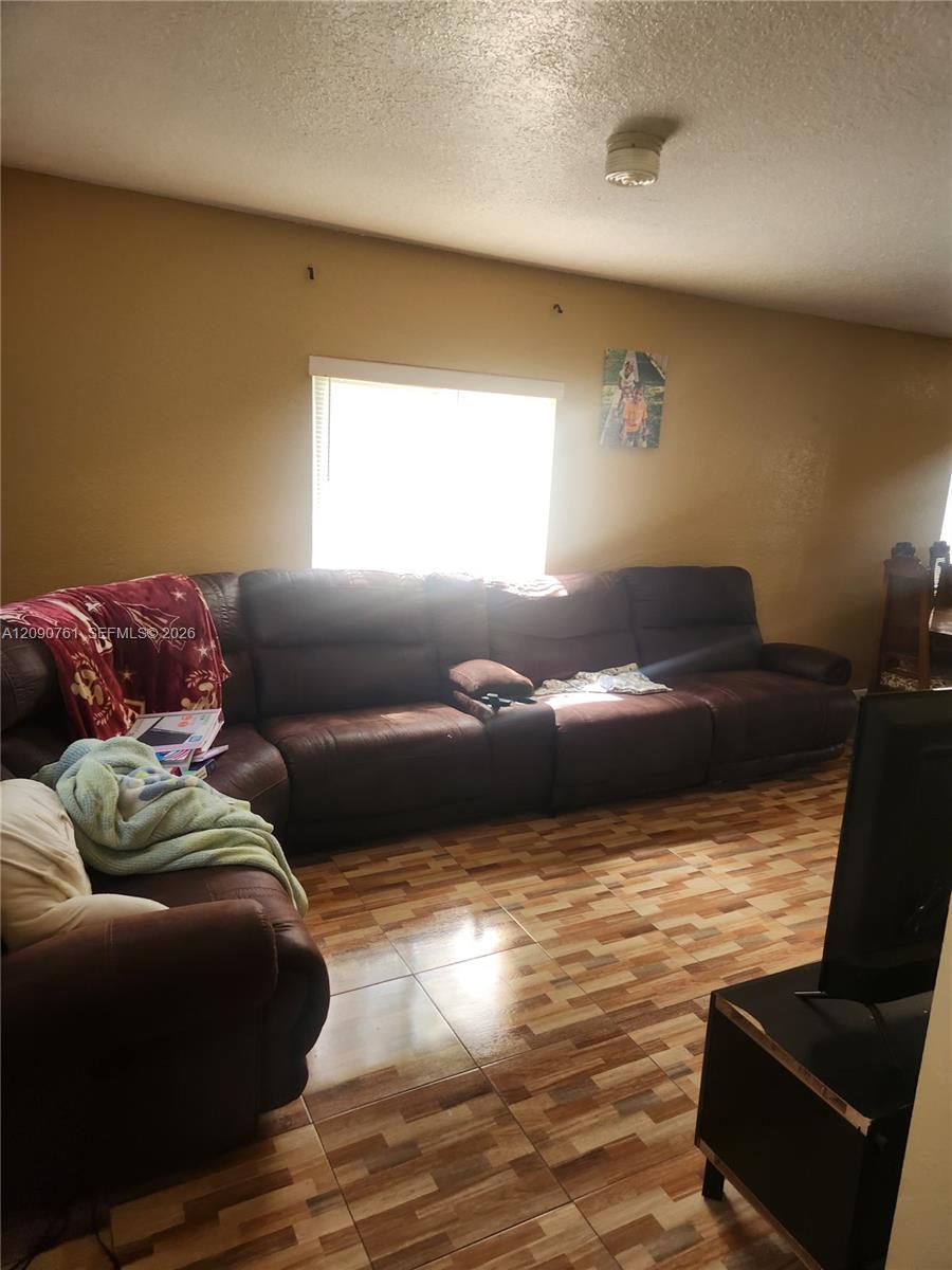 Room interior featuring neutral wall paint, multi-tonal ceramic tile flooring, and a window with horizontal blinds Room interior featuring neutral wall paint, multi-tonal ceramic tile flooring, and a window with horizontal blinds