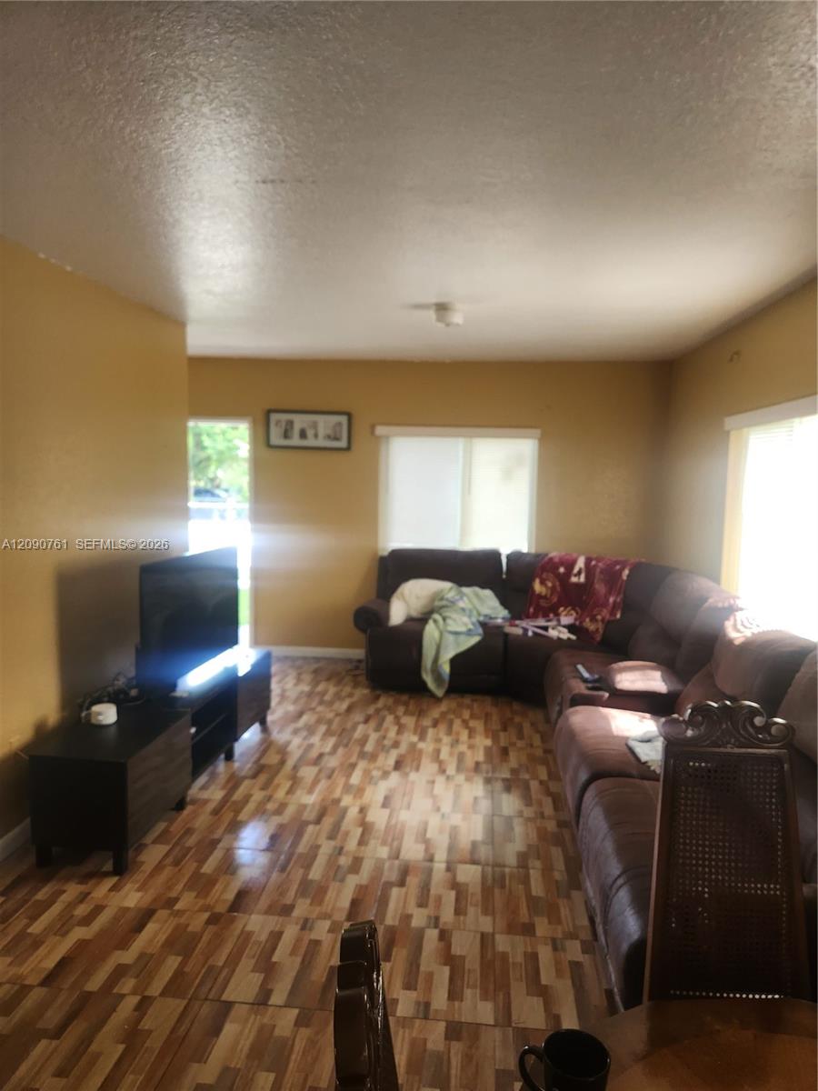 Living area featuring patterned tile flooring and dual windows with horizontal blinds Living area featuring patterned tile flooring and dual windows with horizontal blinds