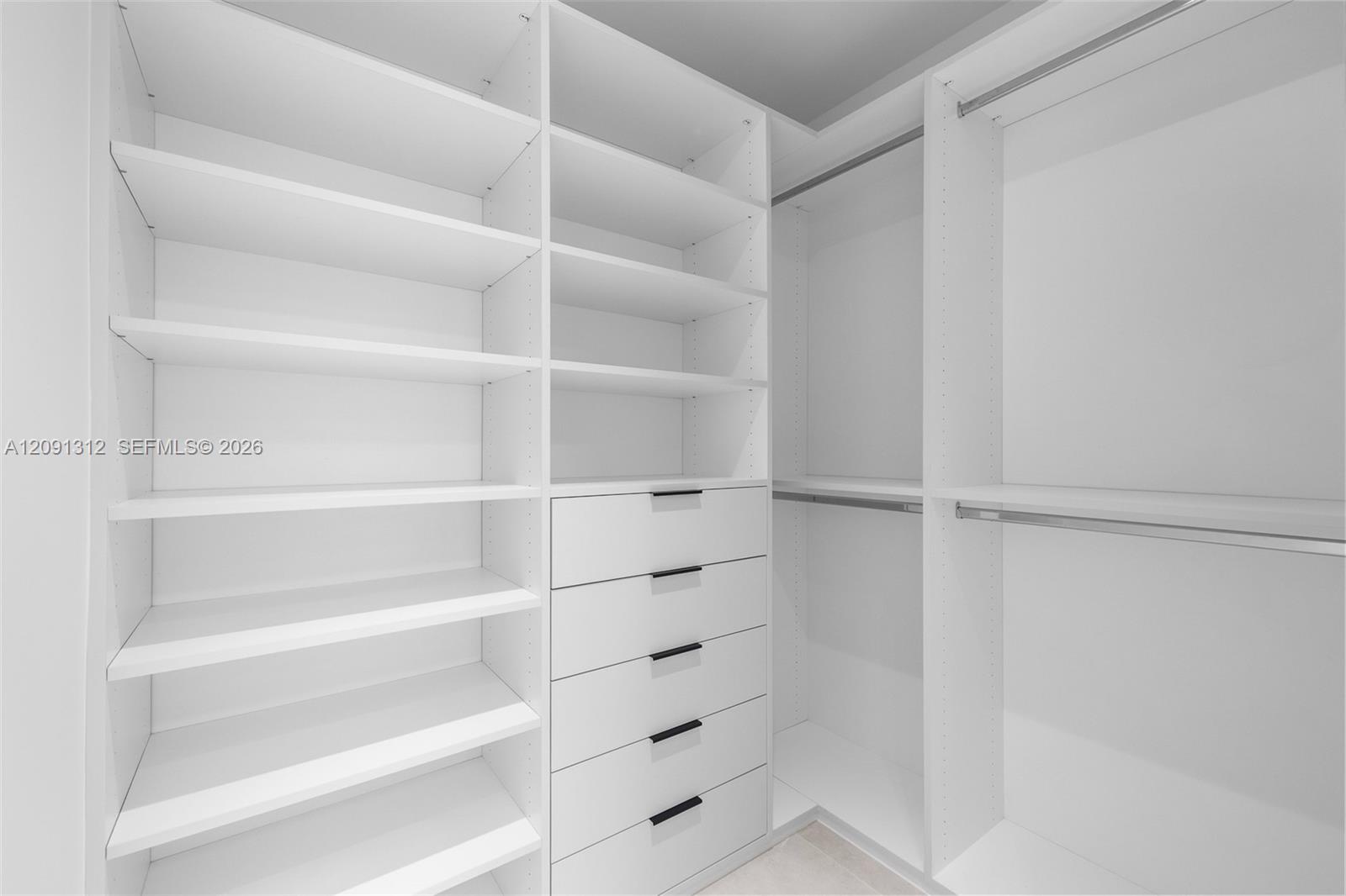 Custom walk-in closet featuring white built-in shelving, a five-drawer dresser unit, integrated hanging rods, and matte black hardware