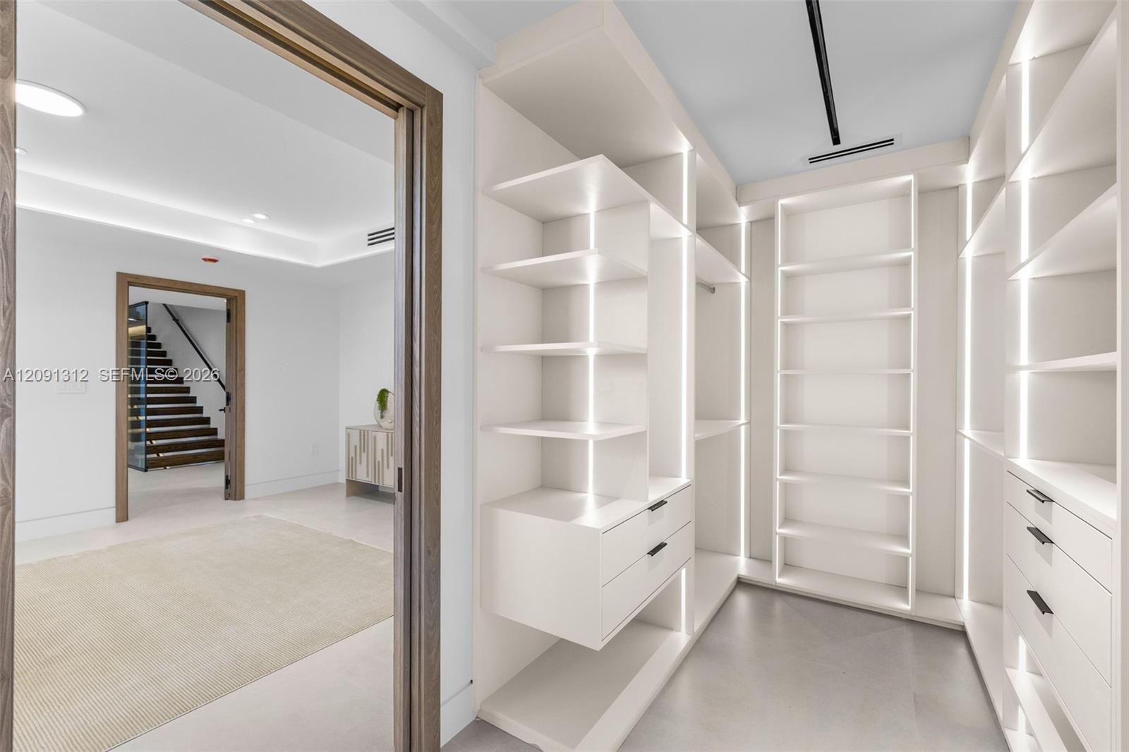 Custom walk-in closet featuring floor-to-ceiling built-in shelving, integrated vertical LED lighting, and drawer storage with matte black hardware