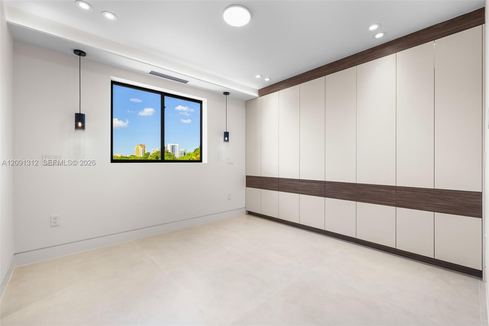 Built-in floor-to-ceiling cabinetry with two-tone finish, large-format tile flooring, dual matte black pendant lights, and recessed ceiling lighting