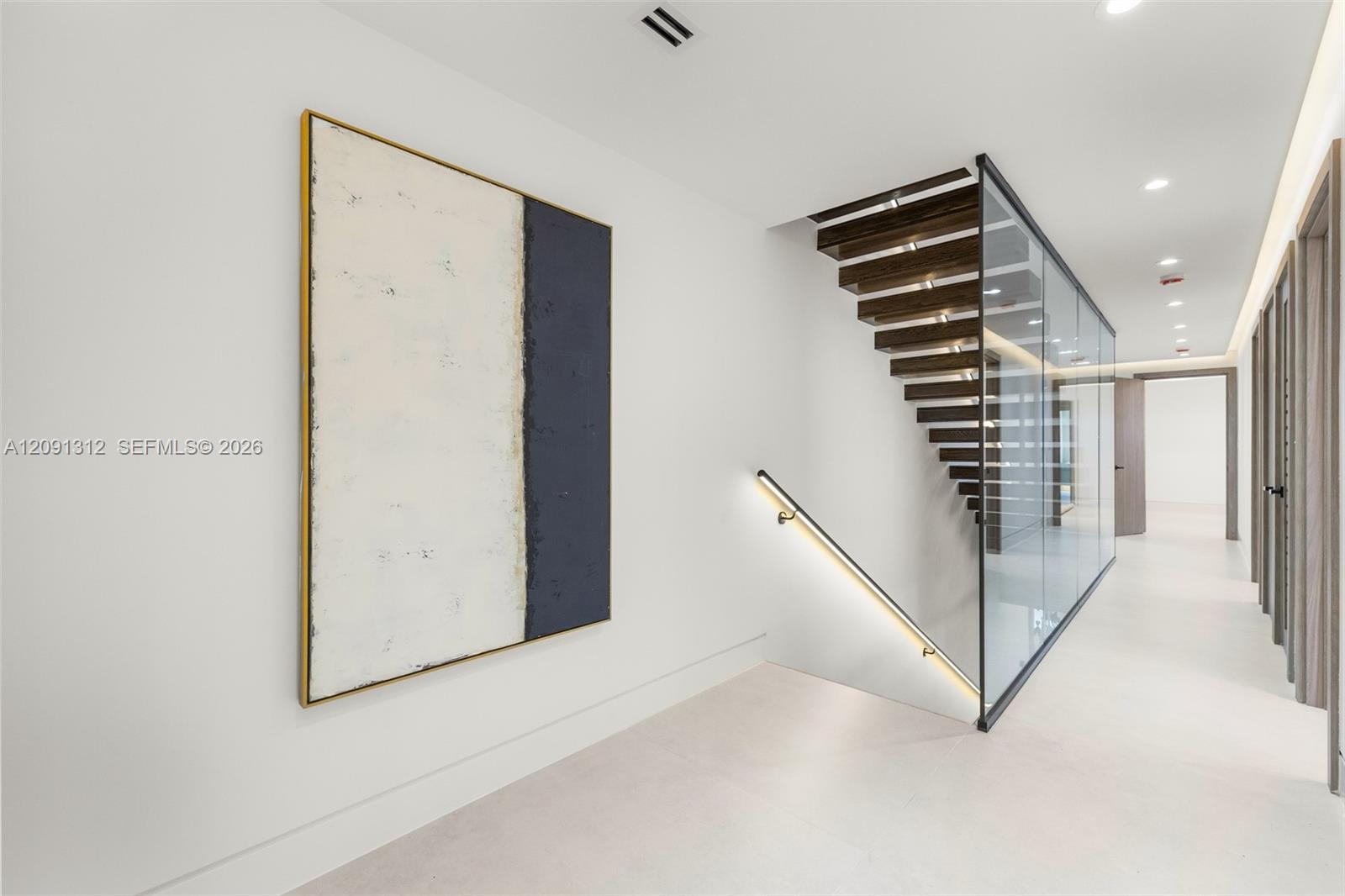 Staircase featuring open-riser wood treads, a full-height glass panel partition, a sleek wall-mounted handrail with integrated LED lighting, and large-format tile flooring