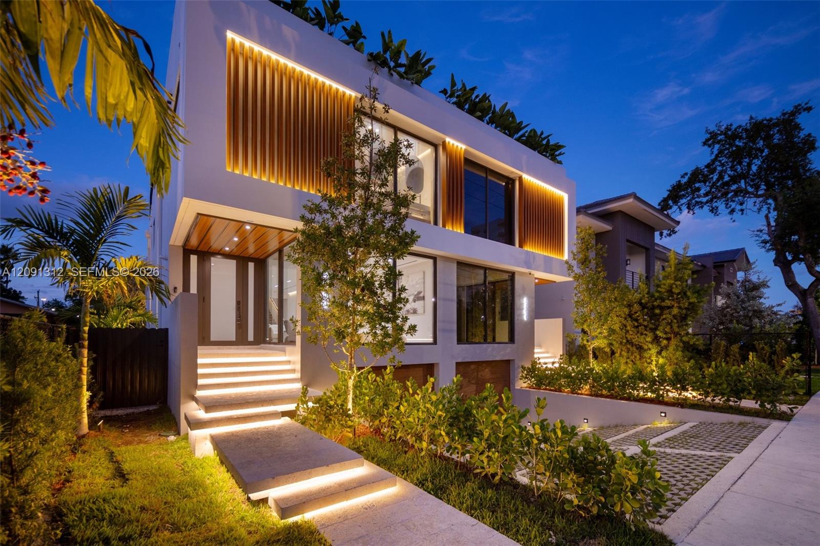 Contemporary multi-story exterior featuring integrated vertical architectural lighting, large-format glass windows, wood-finish paneling, and concrete tiered entry steps
