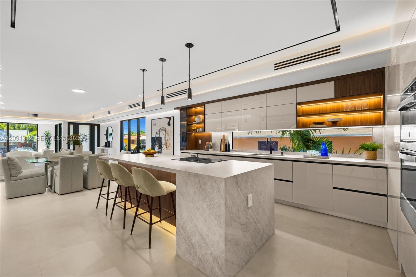Kitchen featuring a stone-topped waterfall island, flat-panel cabinetry, a horizontal window backsplash, integrated under-cabinet lighting, and porcelain tile flooring
