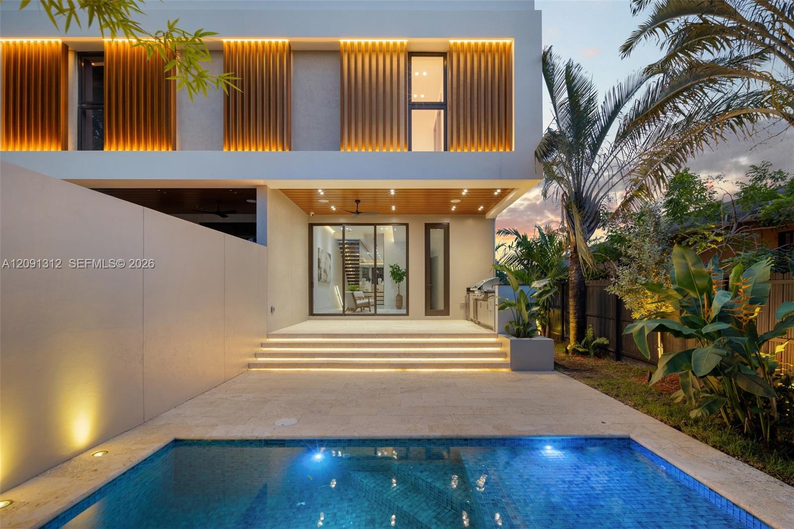Contemporary exterior featuring vertical wood-slat accents, a covered patio with recessed lighting, stone-finish decking, and an in-ground swimming pool