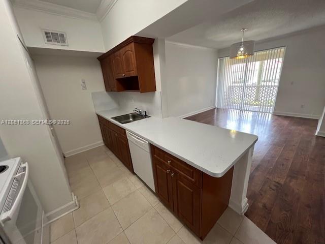 Kitchen featuring wood cabinetry, white solid-surface countertops, tile flooring, and wood-finish flooring in the open area with sliding glass doors
