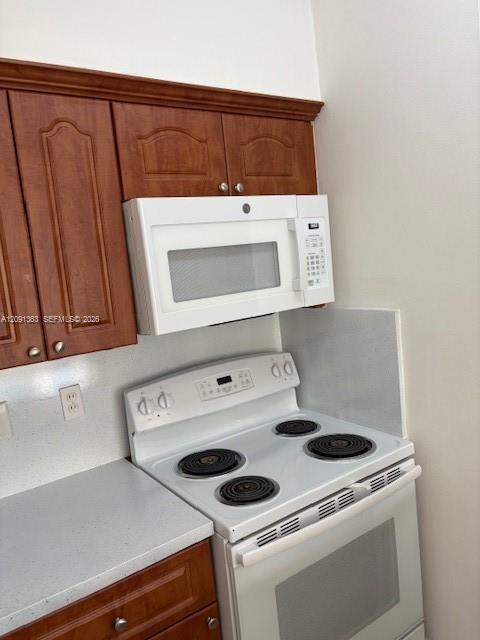 Kitchen featuring raised-panel wood cabinetry with crown molding, white electric range, and over-the-range microwave