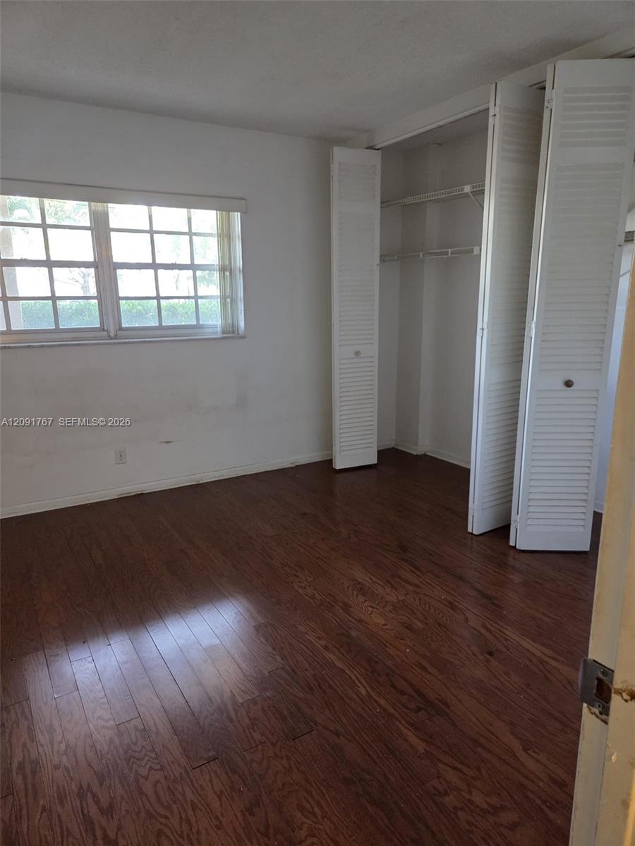 Wood-finish flooring, multi-pane window, and closet featuring white louvered bi-fold doors with built-in wire shelving Wood-finish flooring, multi-pane window, and closet featuring white louvered bi-fold doors with built-in wire shelving