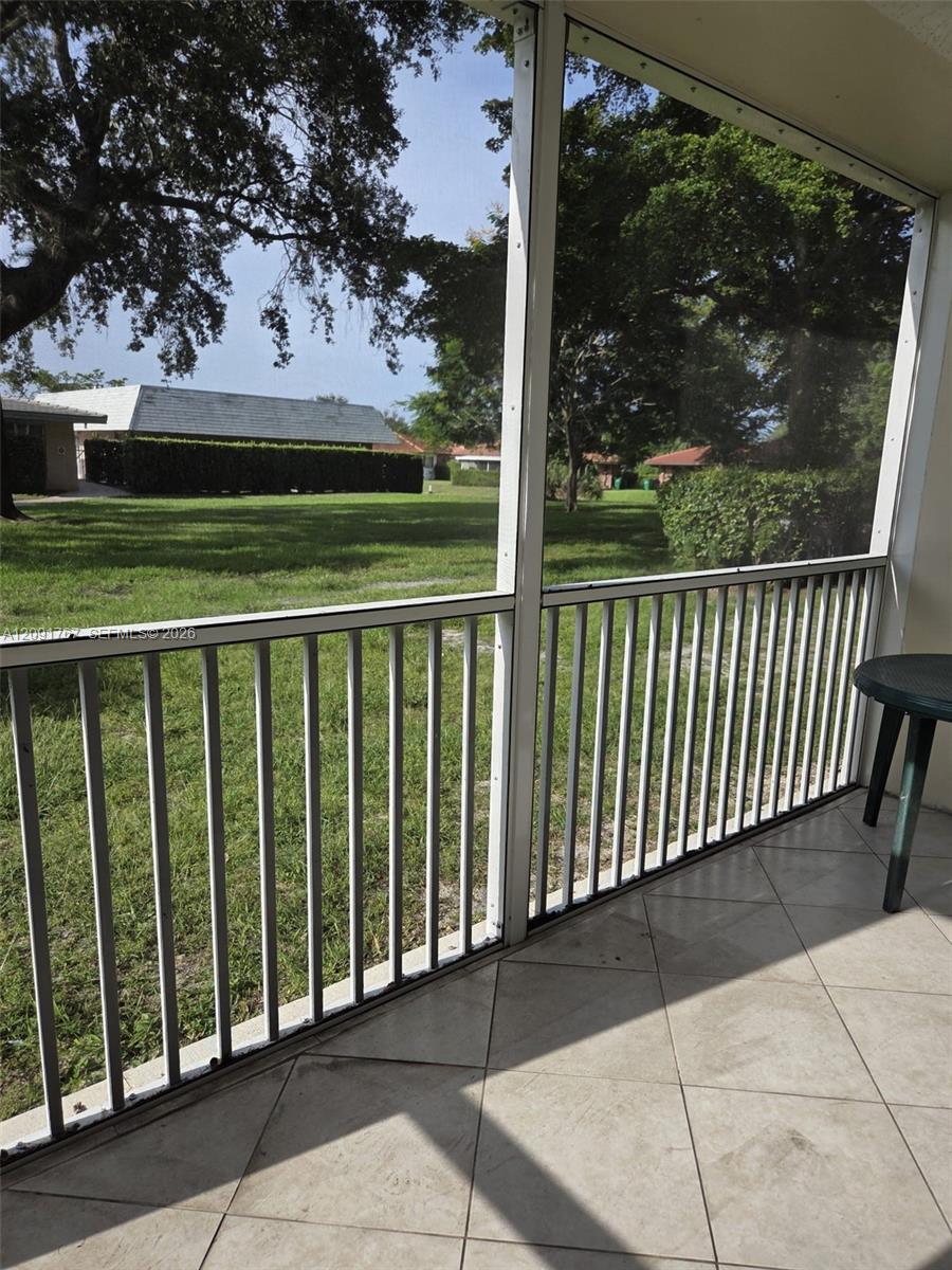 Screened-in porch featuring tile flooring and metal railing