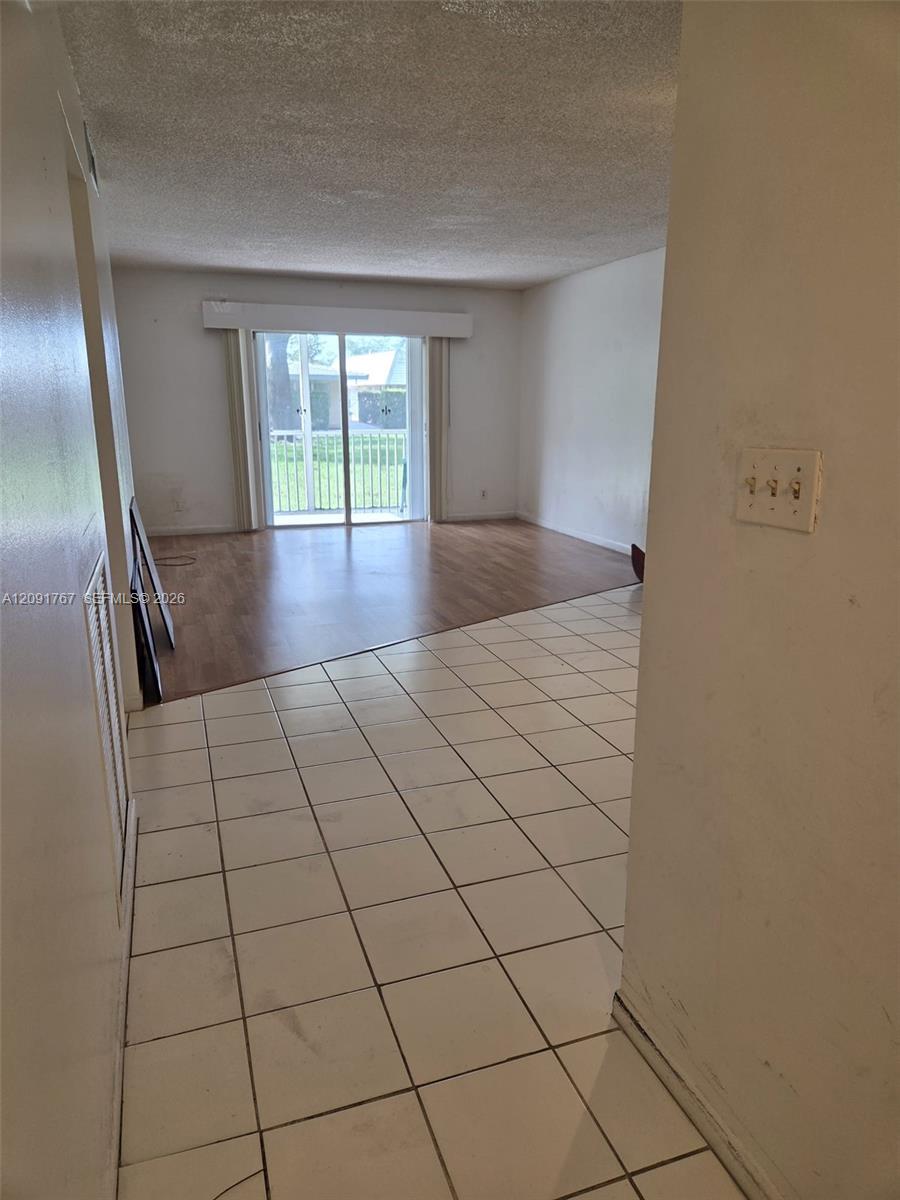 Interior space featuring ceramic tile flooring, wood-finish flooring, and sliding glass doors Interior space featuring ceramic tile flooring, wood-finish flooring, and sliding glass doors