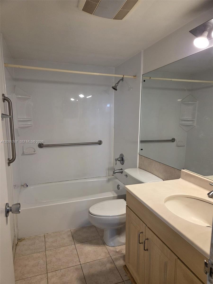 Full-width vanity with integrated countertop and sink, large wall-mounted mirror, tub-shower combination with surround, and ceramic tile flooring Full-width vanity with integrated countertop and sink, large wall-mounted mirror, tub-shower combination with surround, and ceramic tile flooring