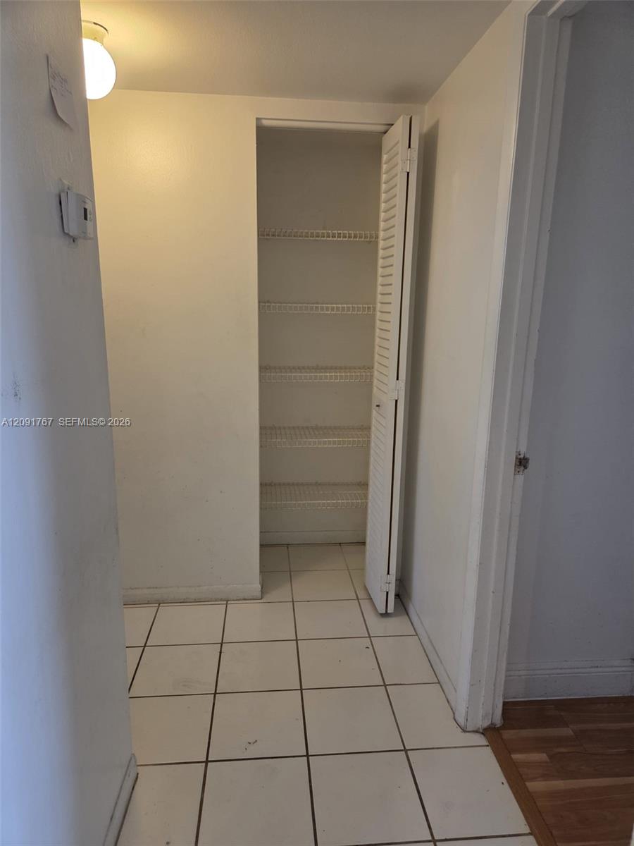 Storage closet featuring louvered bi-fold doors, white wire shelving, and tiled flooring
