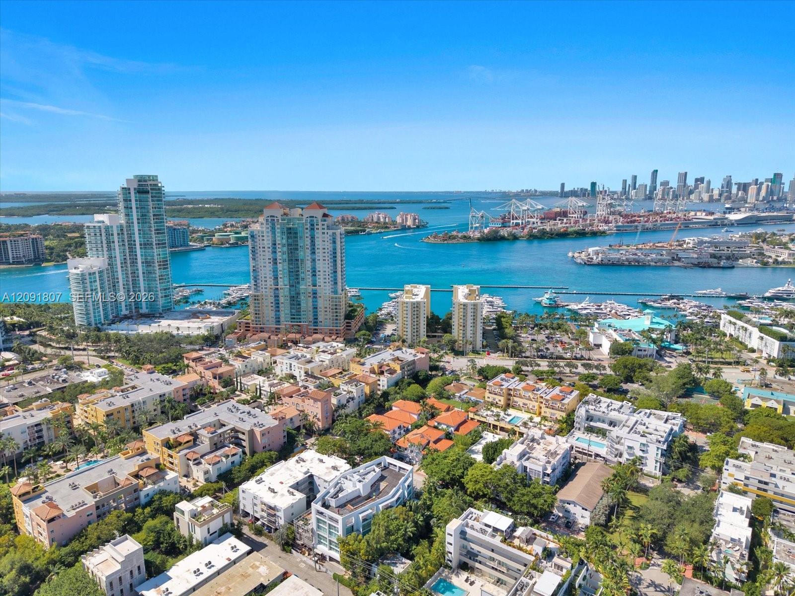 Aerial perspective of a coastal urban landscape featuring high-rise buildings, expansive harbor waterways, boat slips, and mature tropical greenery