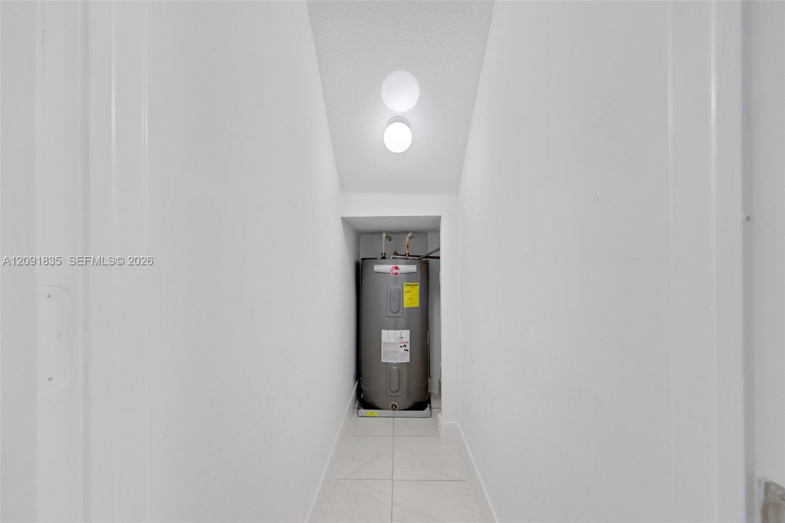 water heater, white tile flooring, and a ceiling-mounted light fixture