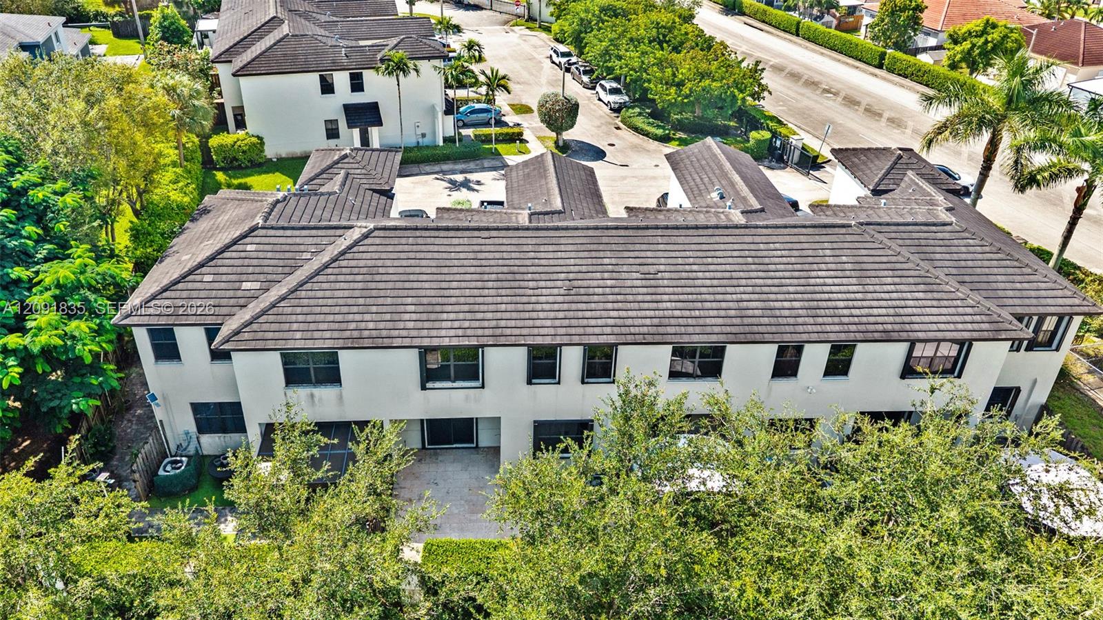 Multi-level exterior featuring a hipped tile roof, smooth stucco facade, and paved patio area