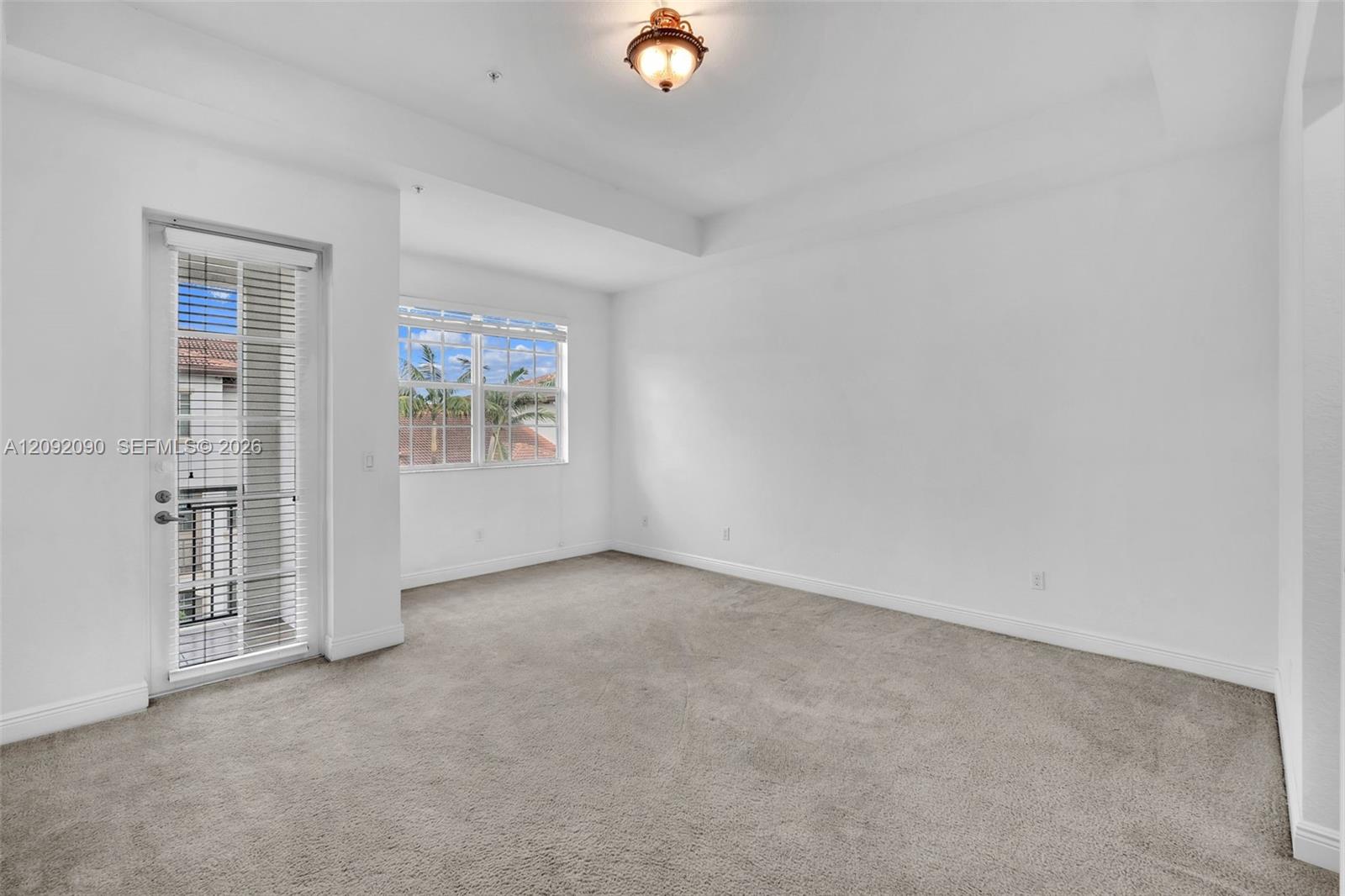Tray ceiling, wall-to-wall carpeting, multi-pane windows, and a glass-paneled exterior door featuring a metal balcony railing