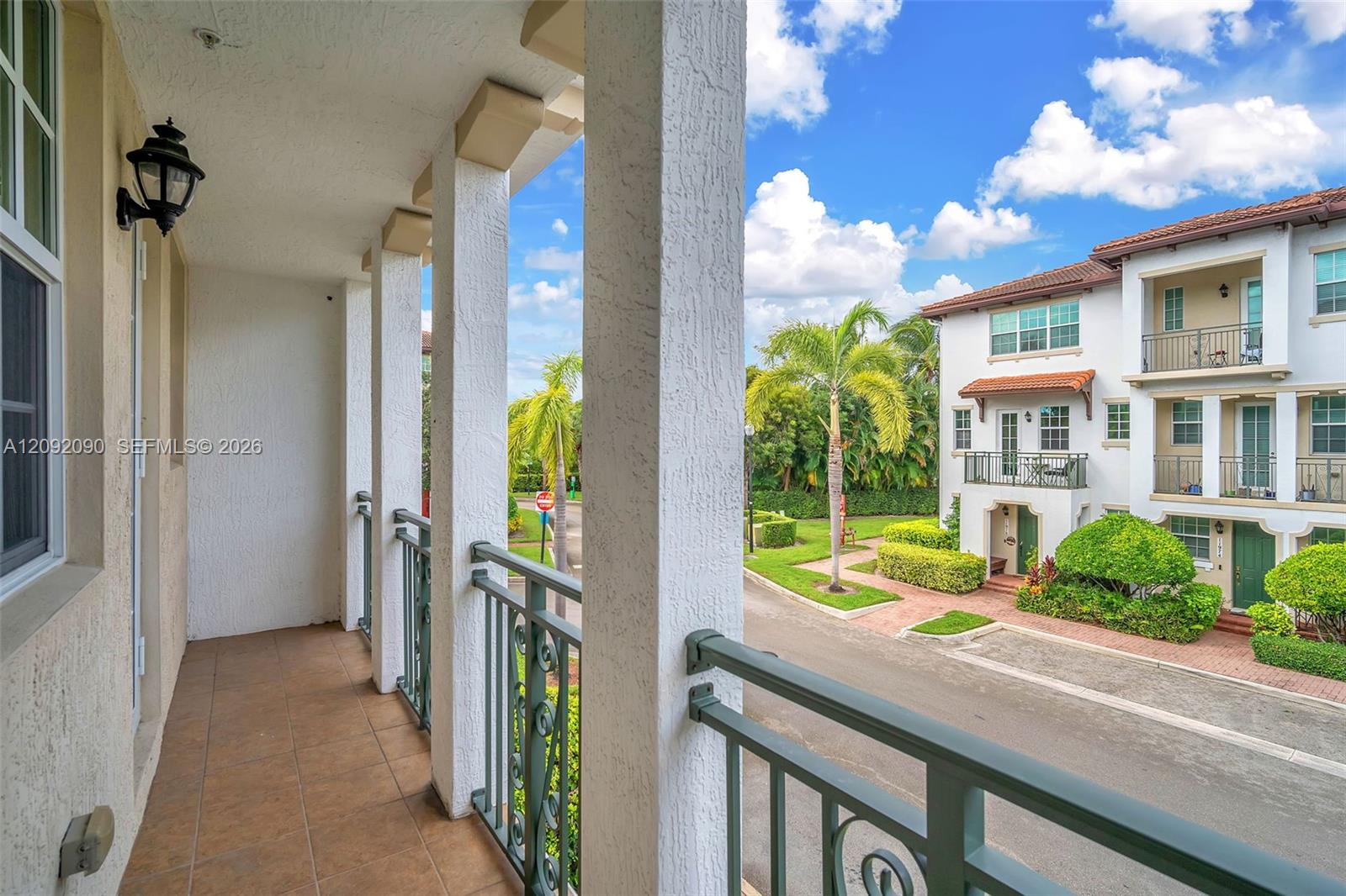 Covered balcony featuring tile flooring, structural columns, and a decorative metal railing