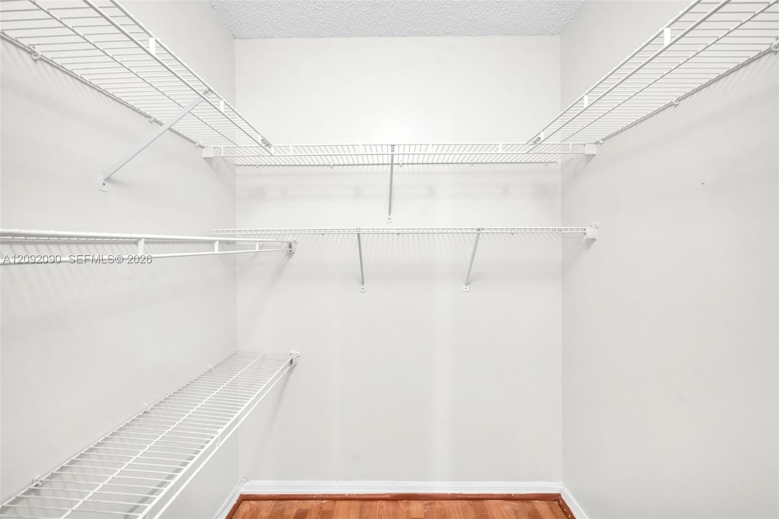 Storage area featuring multiple tiers of white wire shelving and wood-finish flooring