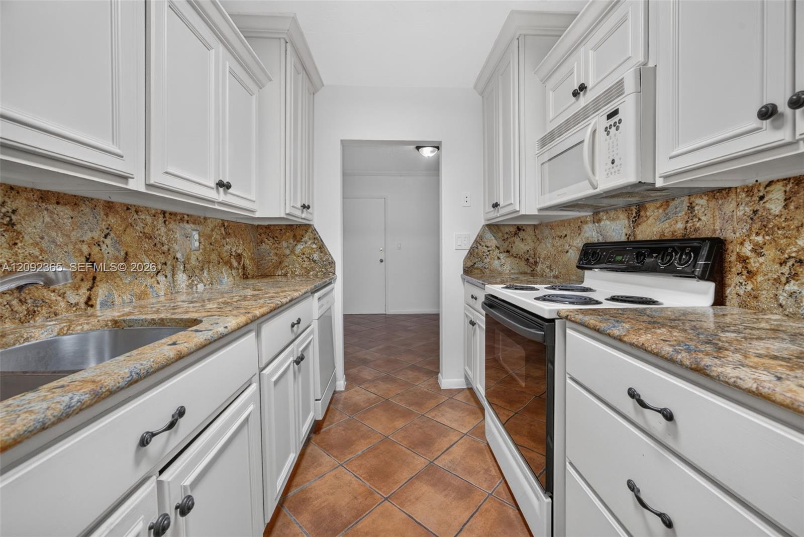 Galley-style kitchen featuring wood cabinetry & granite countertops
