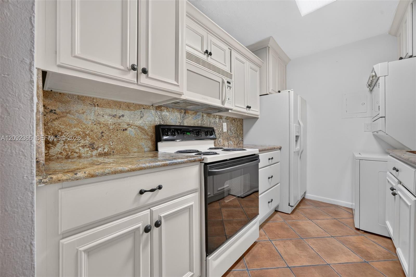 Galley-style kitchen featuring wood cabinetry & granite countertops