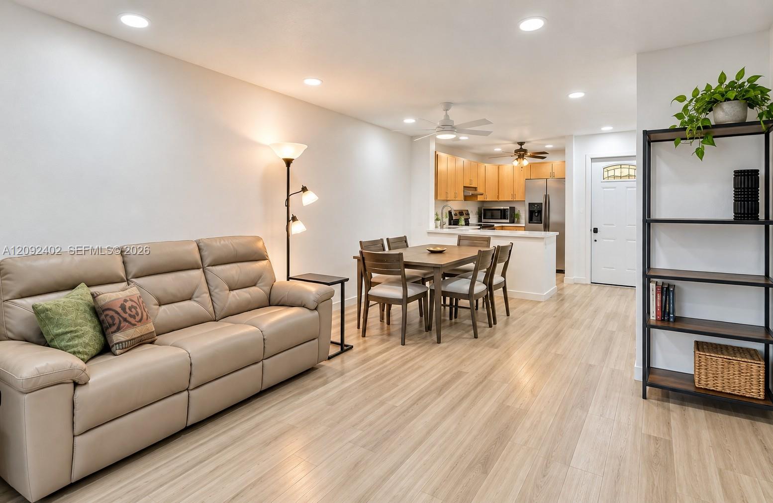 Open-concept interior featuring wood-finish flooring, recessed lighting, and kitchen cabinetry with stainless steel appliances