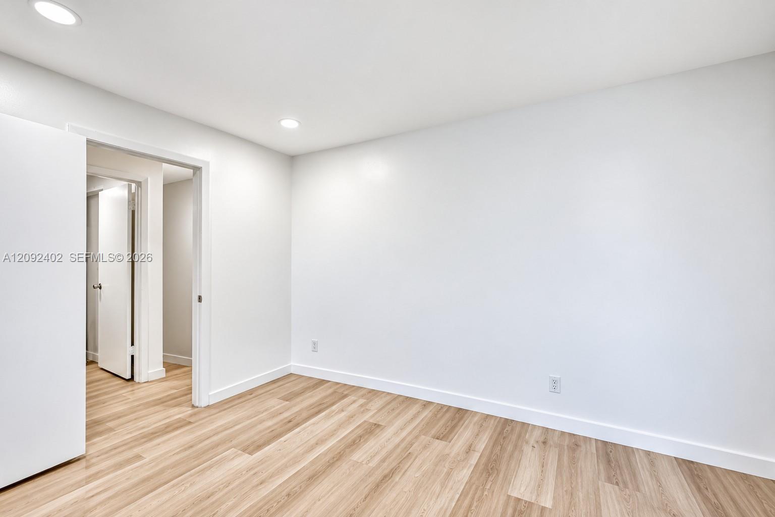 Interior space featuring wood-finish flooring, crisp white walls, and recessed ceiling lighting