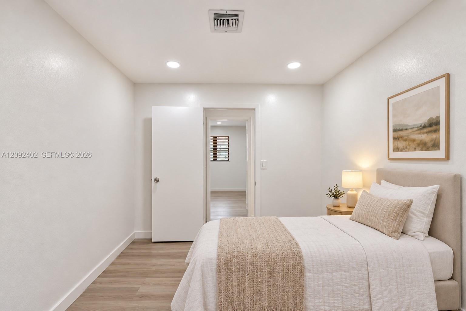 TV console & plants virtually staged for illustrative purposes. Neutral-toned walls, wood-finish flooring, recessed lighting, and a crisp white interior door