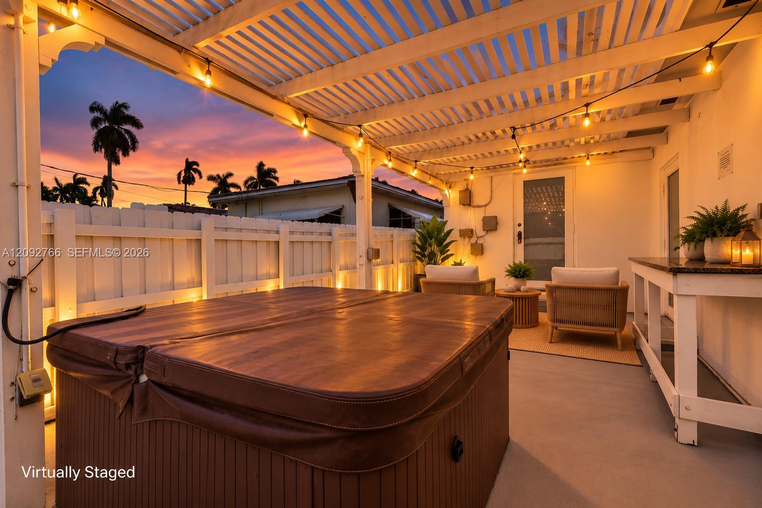Covered outdoor patio featuring a pergola, built-in hot tub, concrete flooring, and privacy fencing