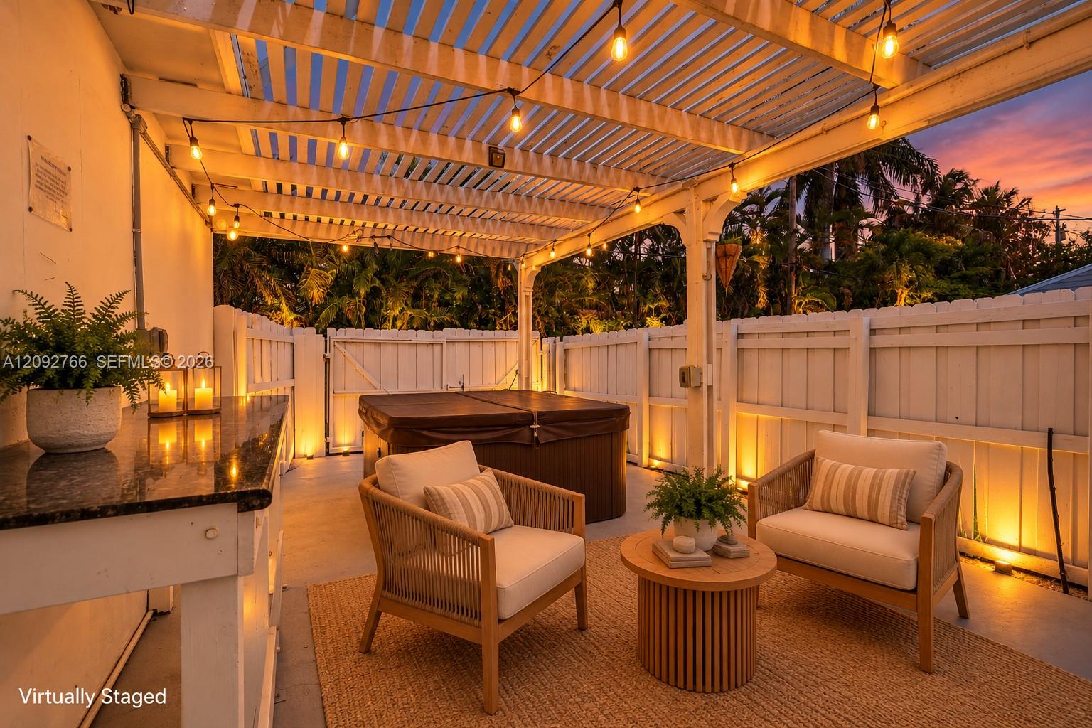 Covered pergola patio featuring integrated string lighting, built-in stone-top prep counter, and a private fenced perimeter