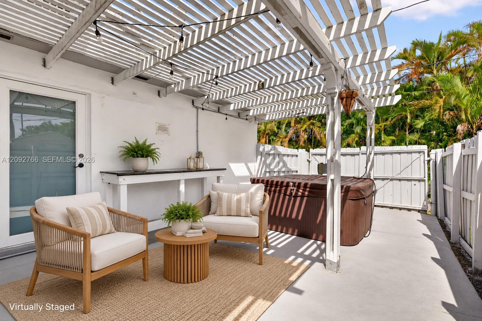 Outdoor patio featuring a white pergola, concrete flooring, built-in shelving, and a jetted spa