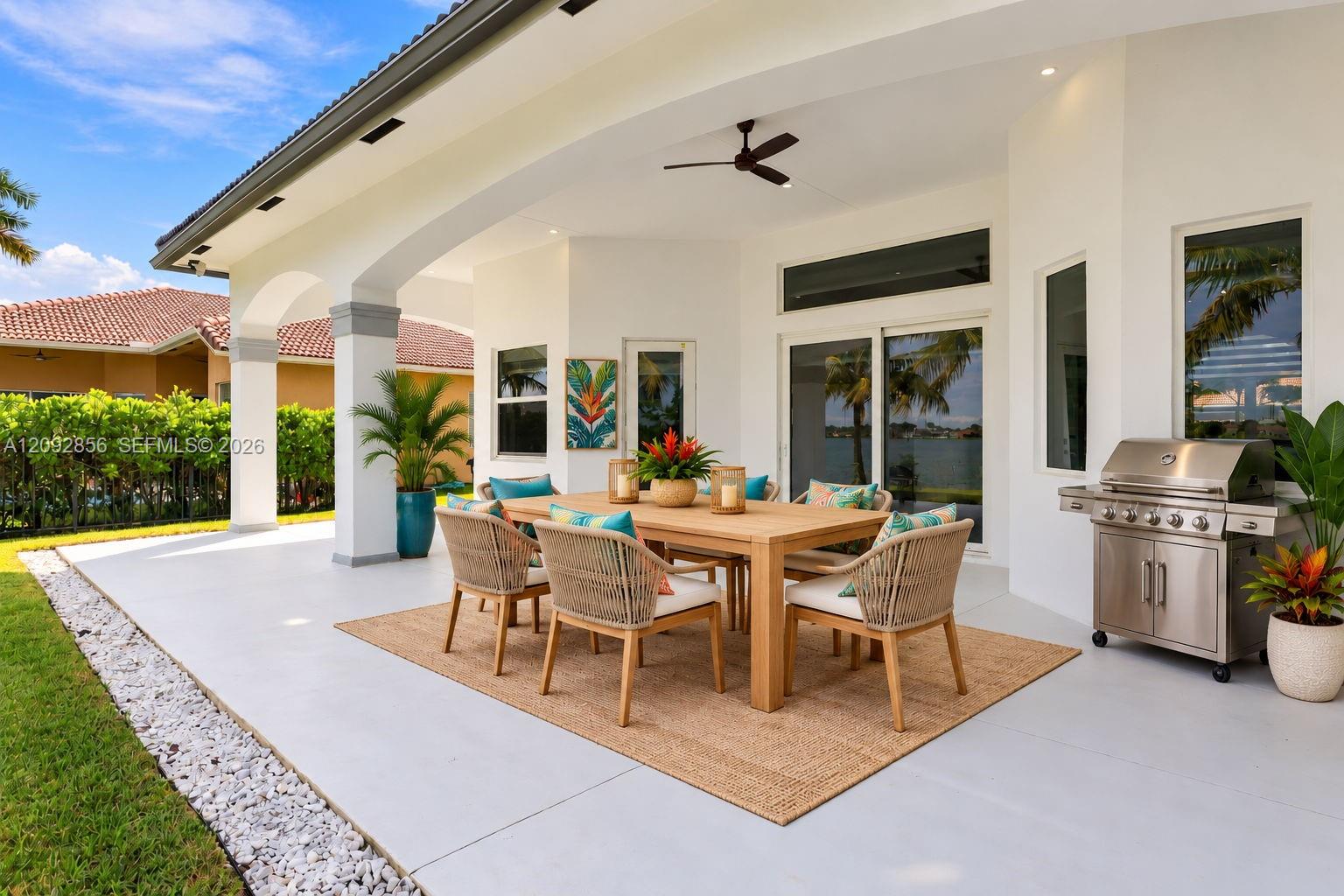 Virtually staged - covered outdoor patio featuring arched architectural columns, recessed ceiling lighting, a matte black ceiling fan, and a built-in stainless steel grill