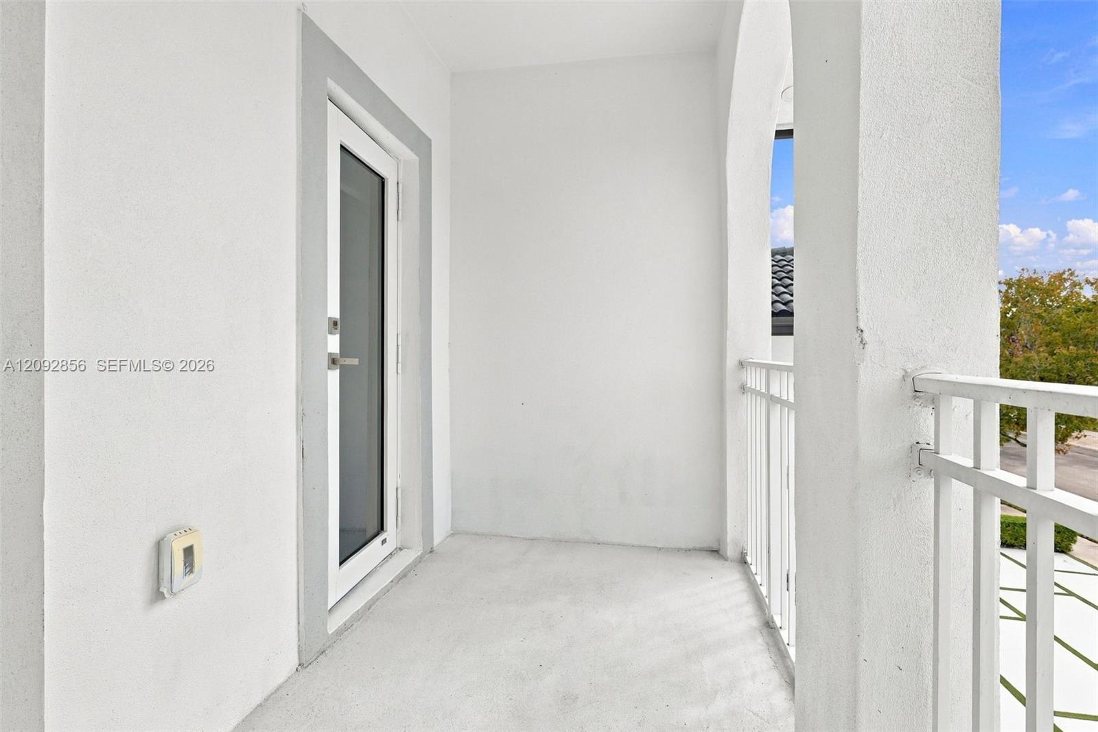 5th bedroom - Covered balcony featuring stucco walls, an arched opening, and a white metal railing