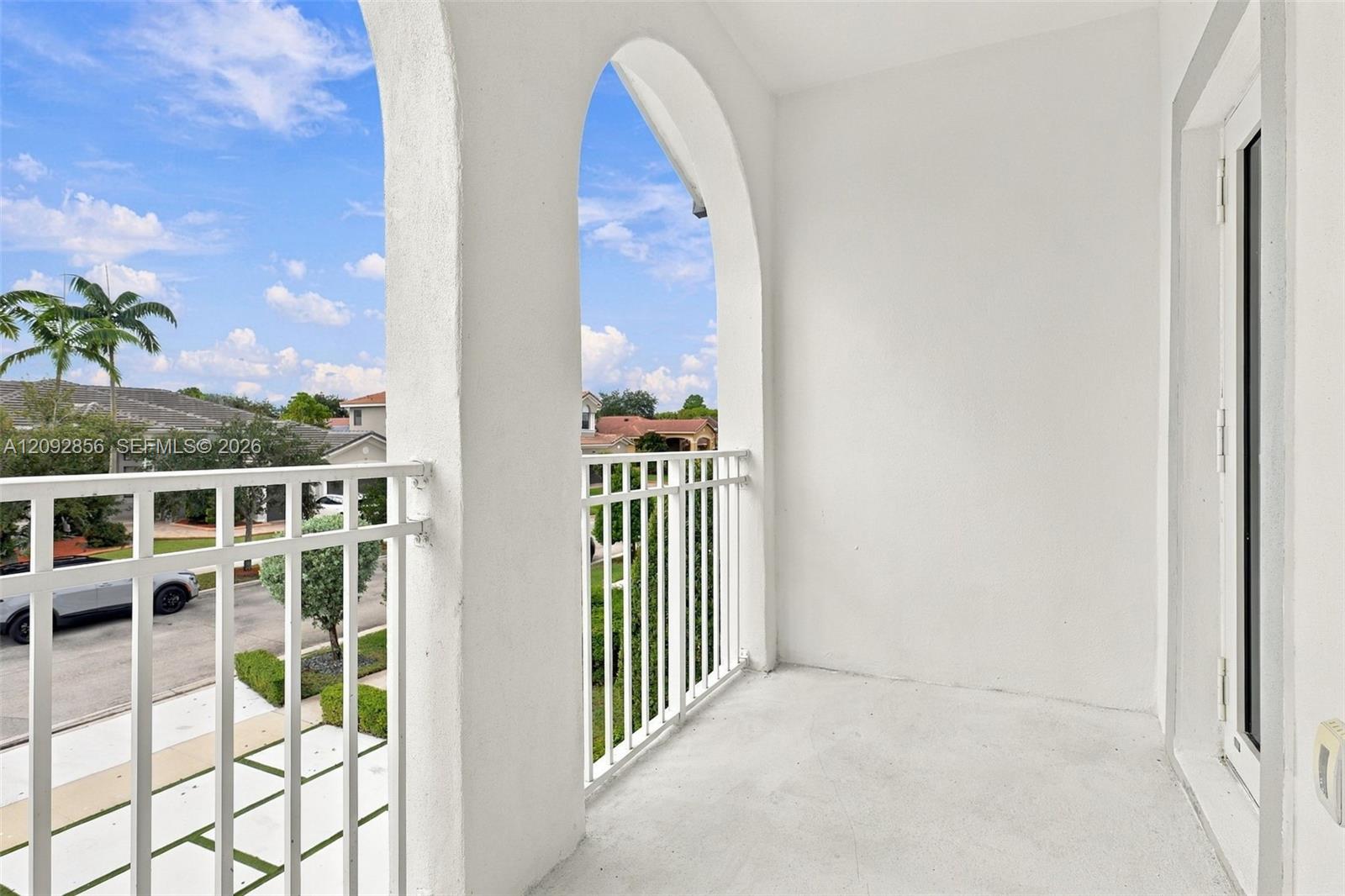 5th bedroom - Covered balcony featuring arched architectural detailing, a solid concrete floor, and white metal railing