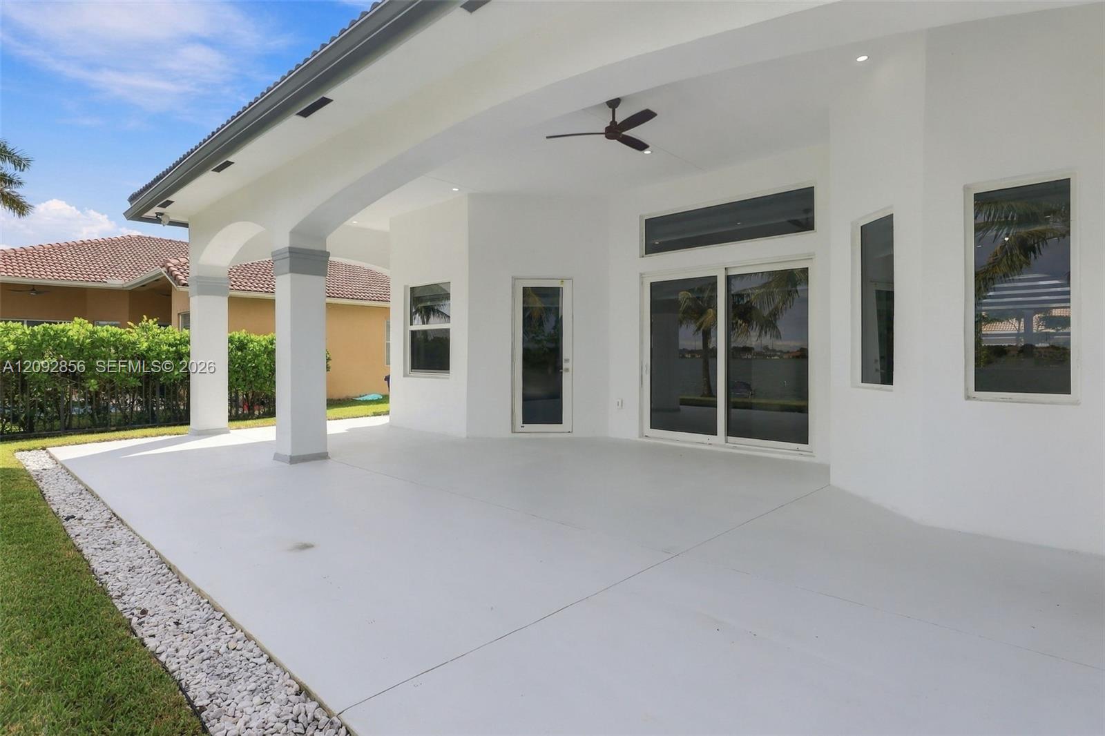 Covered patio featuring arched architectural columns, recessed lighting, a ceiling fan, and sliding glass doors