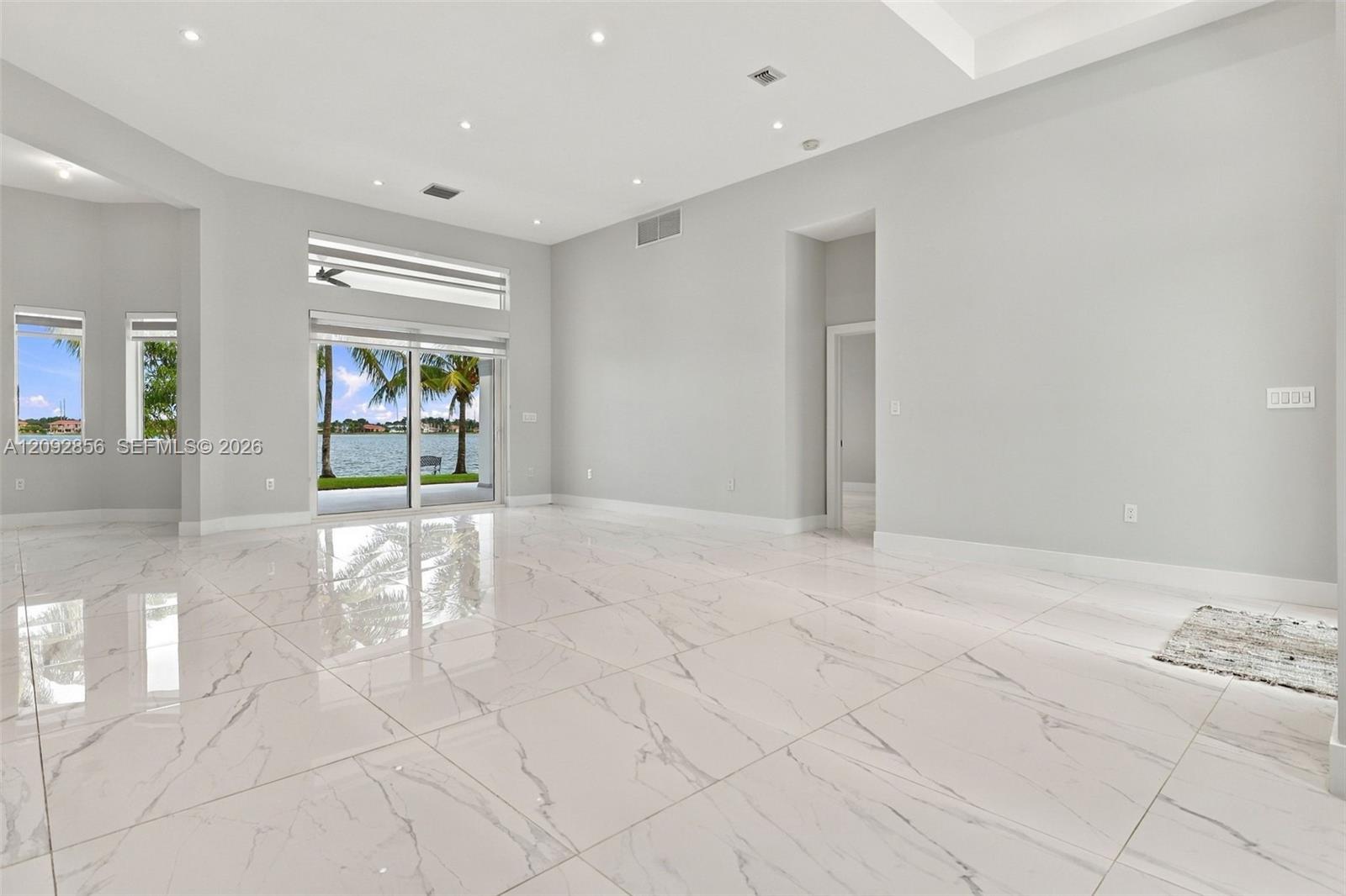 Spacious interior featuring large-format stone-finish tile flooring, vaulted ceilings, recessed lighting, and expansive glass sliding doors