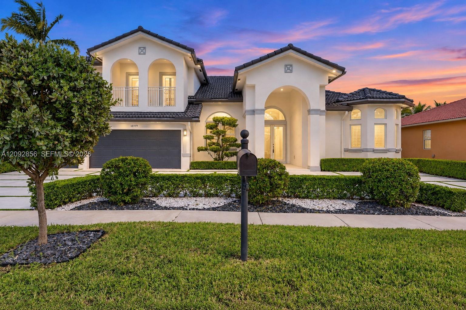 Mediterranean-style exterior featuring a stucco facade, arched entryway, upper-level balcony, tile roof, and a multi-car garage Mediterranean-style exterior featuring a stucco facade, arched entryway, upper-level balcony, tile roof, and a multi-car garage