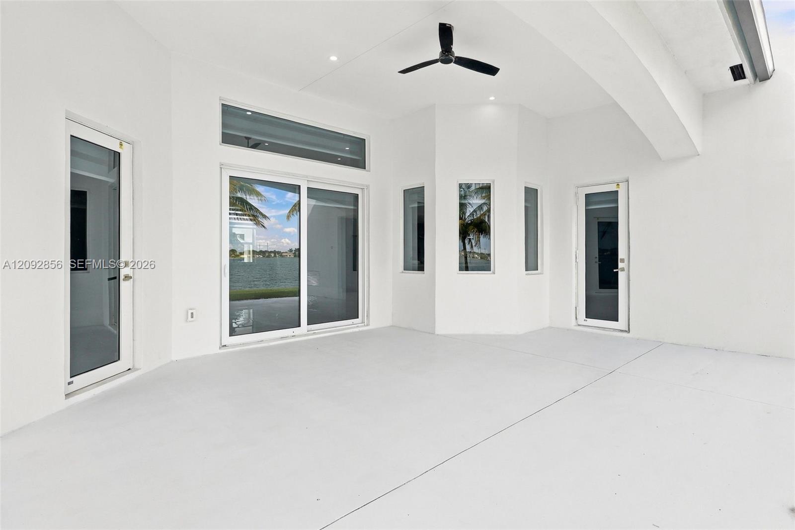 Covered patio featuring a high vaulted ceiling, integrated ceiling fan, recessed lighting, expansive glass sliding doors, and multiple casement windows