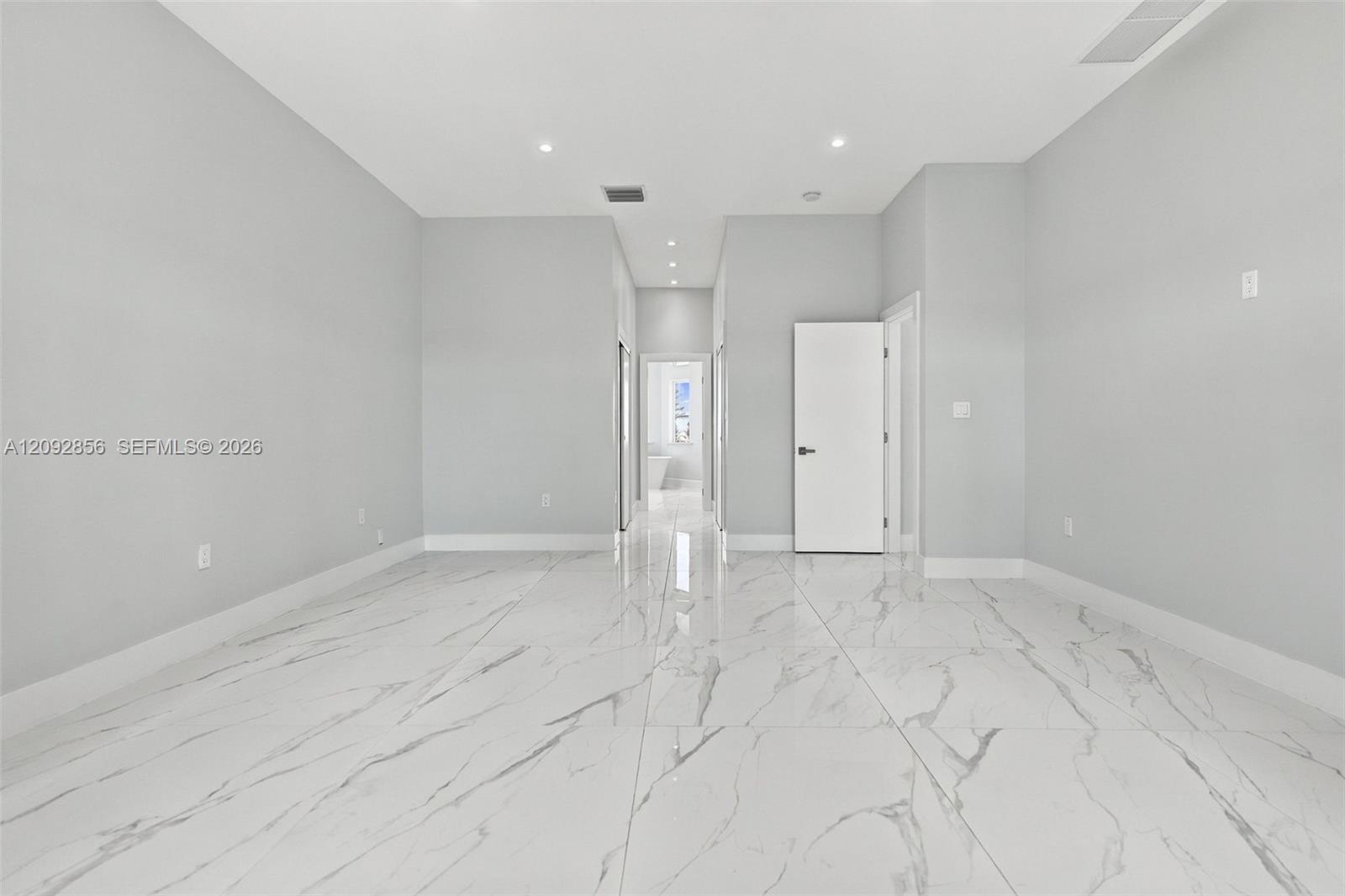 Neutral interior featuring polished large-format tile flooring with veining, recessed lighting, and solid-core doors