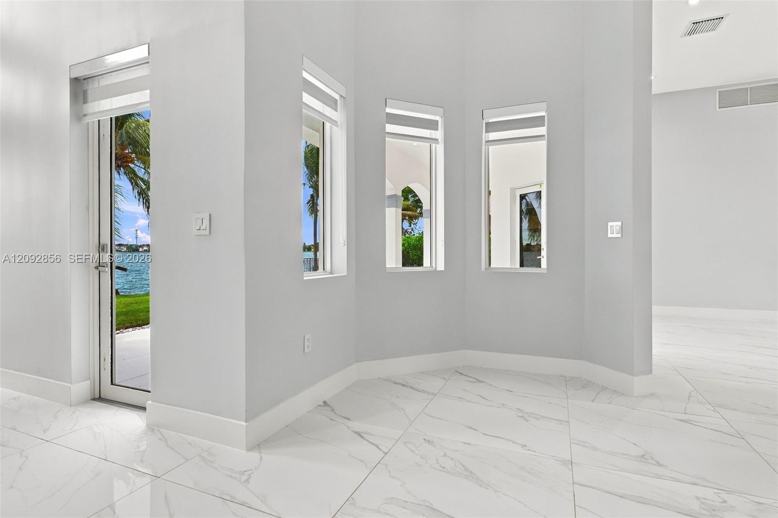 Large-format white stone-finish flooring with grey veining, crisp white walls, and multiple floor-to-ceiling windows